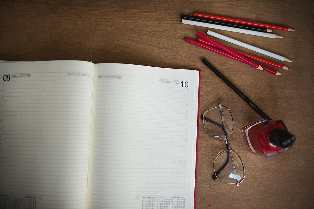 Caderno aberto, lápis de cor e óculos sobre a mesa